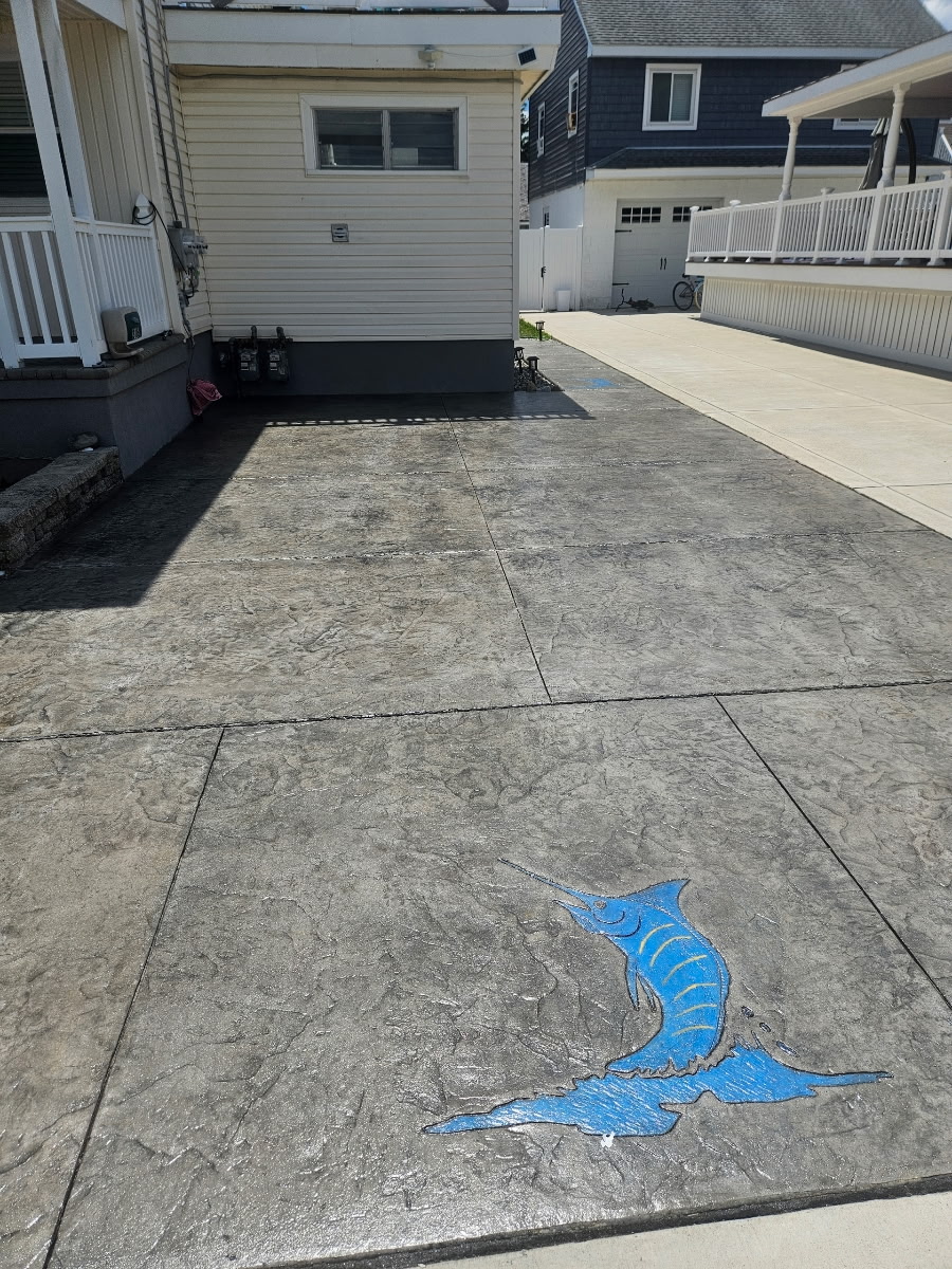 Restored stamped concrete driveway with rich color and custom marlin accent