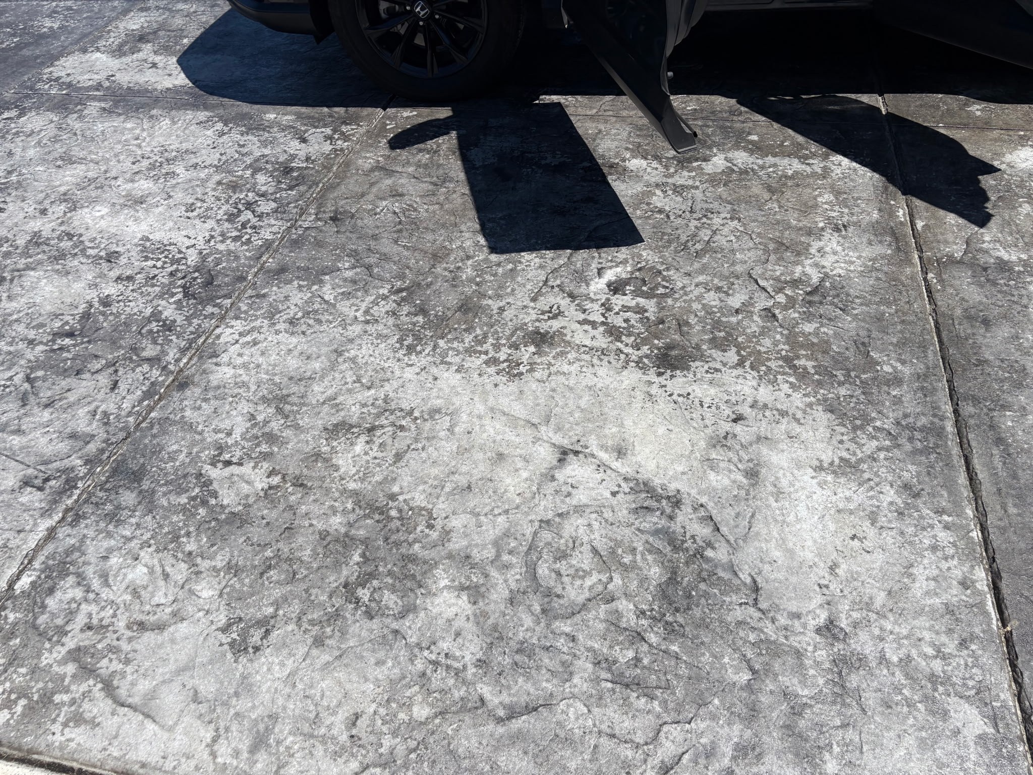 Faded, weathered stamped concrete driveway before restoration